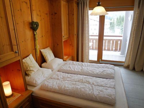 ein Schlafzimmer mit einem weißen Bett und einem Fenster in der Unterkunft Apartment Chesa Boffalora by Interhome in Valbella