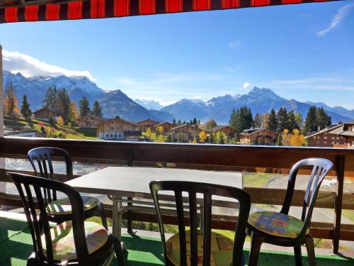 een tafel en stoelen op een balkon met uitzicht op de bergen bij Apartment Diamant 39 by Interhome in Villars-sur-Ollon