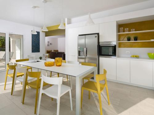 a kitchen and dining room with a white table and yellow chairs at Villa Debora by Interhome in Diminići