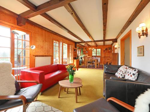 a living room with a red couch and a table at Chalet L'Oiselet by Interhome in Villars-sur-Ollon
