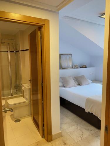 a bedroom with a bed and a bathroom with a shower at Apartamento Marina Llanes III in Llanes