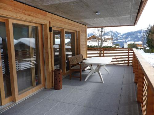 a patio with a table and a bench on a deck at Apartment Jardins d'Helene by Interhome in Ovronnaz