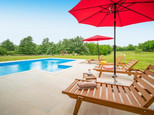 a patio with a red umbrella and a pool at Holiday Home Villa Frankovići by Interhome in Brajkovići