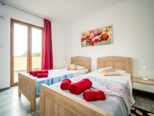 two beds in a room with red pillows on them at Holiday Home Villa Frankovići by Interhome in Brajkovići