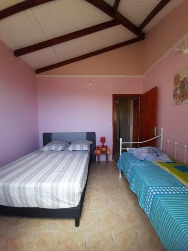 Twee bedden in een slaapkamer met roze muren. bij Pomme cannelle in Bouillante