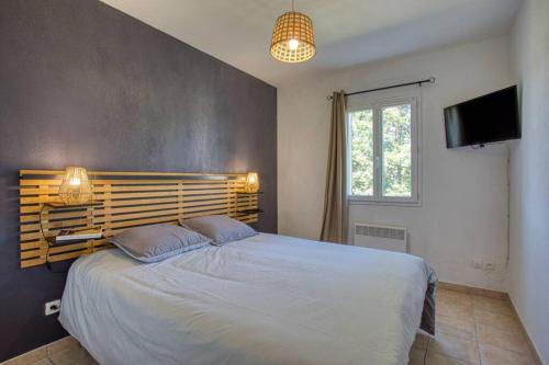 een slaapkamer met een groot bed en een televisie bij SARLAT - 24 - L'appartement d'Euphé avec piscine in Sarlat-la-Canéda