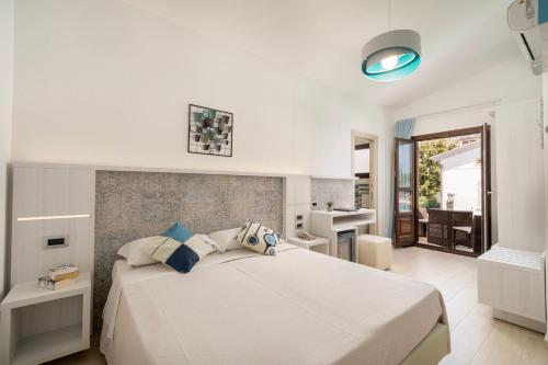 a bedroom with a large white bed and a bathroom at Hotel Ristorante La Conchiglia in Cala Gonone