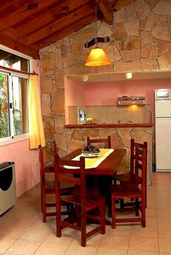 a kitchen with a table and chairs and a stone wall at Cabañas Mellmell in Mar de las Pampas