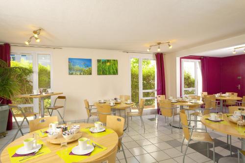 a restaurant with tables and chairs and windows at Séjours & Affaires Toulouse de Brienne in Toulouse