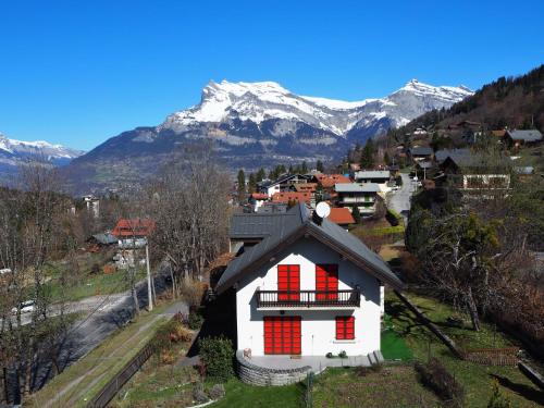 une maison avec des fenêtres rouges et des montagnes en arrière-plan dans l'établissement Apartment Les gentianes by Interhome, à Saint-Gervais-les-Bains