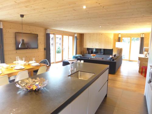 a kitchen and living room with a table and a couch at Chalet Chalet Astoria by Interhome in Crans-Montana