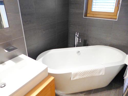 a bathroom with a white tub and a sink at Chalet Chalet Astoria by Interhome in Crans-Montana