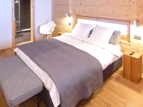 a bedroom with a large bed and a chair at Chalet Chalet Astoria by Interhome in Crans-Montana