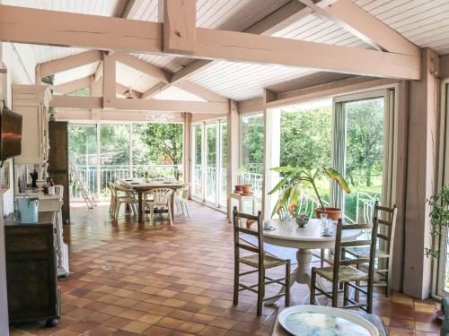 un giardino d'inverno con tavoli, sedie e finestre di Holiday Home Crabot by Interhome a Saint-Vivien-de-Médoc