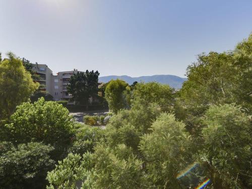a group of trees with a building in the background at Apartment Porto di Mar-10 by Interhome in Cavalaire-sur-Mer