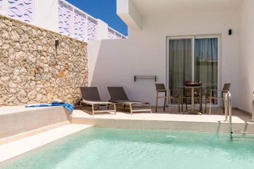 a villa with a swimming pool and a table and chairs at Stay Helios in Faliraki