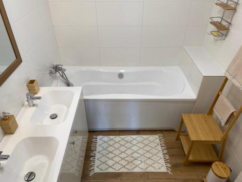 a white bathroom with a tub and a sink at Várárok Vendégház - Miskolc in Miskolc