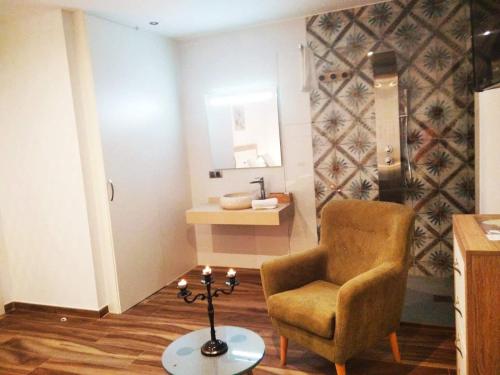 a living room with a chair and a table at Restaurante & Hotel Rural El Mirador de Trevejo,ideal para parejas in Villamiel