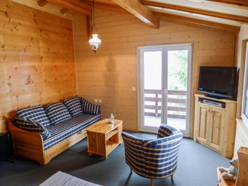 a living room with a couch and a tv at Holiday Home Chalet Ninette by Interhome in Eischoll