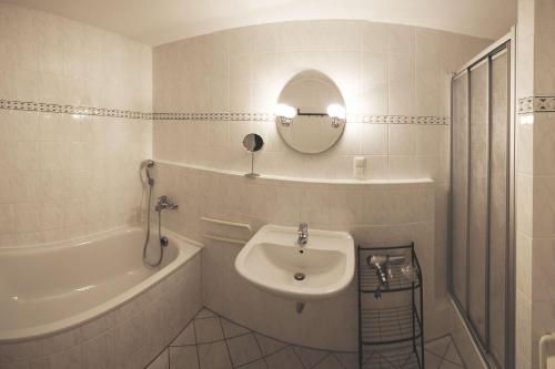 a bathroom with a sink and a tub and a mirror at Ferienwohnung am Potenberg FeWo 6 - Balkon in Binz