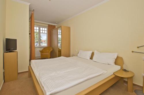 Schlafzimmer mit einem großen weißen Bett und einem TV in der Unterkunft Villa Laetitia FeWo 16 - strandnah, Balkon in Binz