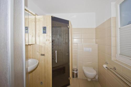 a bathroom with a toilet and a sink and a shower at Ferienhaus Cumulus Haus - strandnah, Terrasse, Sauna in Drewoldke