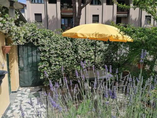 un parasol dans un jardin avec des fleurs violettes dans l'établissement Eco Pisa Tower Guesthouse, à Pise