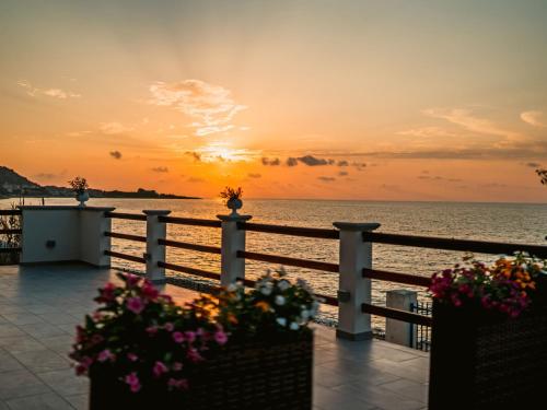 einen Sonnenuntergang über dem Meer mit Blumen auf einem Zaun in der Unterkunft Apartment Nina by Interhome in Caronia Marina