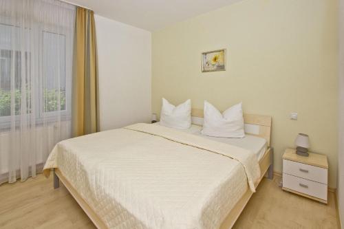 une chambre avec un lit avec des draps blancs et une fenêtre dans l'établissement zentral aber ruhig, Balkon, gratis Nutzung vom AHOI Erlebnisbad und Sauna in Sellin - Villa Elisenhof FeWo 2, à Göhren