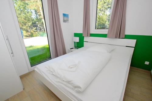 a white bed in a room with large windows at strandnahes Ferienhaus mit eigener Sauna und Kamin - Ferienhaus am Dünenstrand in Baabe