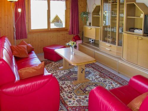 uma sala de estar com cadeiras vermelhas e uma mesa em Apartment Fortuna by Interhome em Grächen