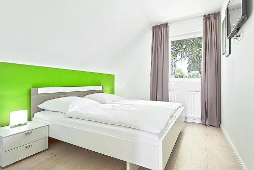 a white bed with a green headboard in a bedroom at Ferienhaus Mantje Mantje Haus - Meerblick, Sauna, Terrasse in Gager