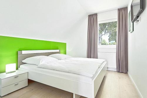 ガガーにあるFerienhaus Mantje Mantje Haus - Meerblick, Sauna, Terrasseの白いベッド(緑のヘッドボード付)が備わるベッドルームです。
