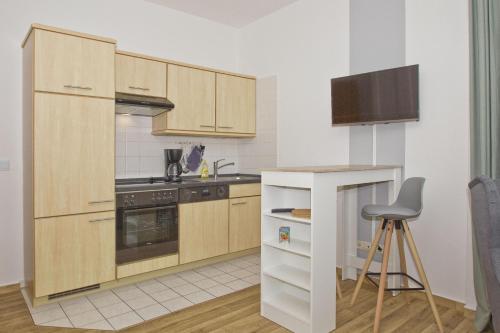 a kitchen with wooden cabinets and a chair in it at Haus Brandenburg FeWo 37 - strandnah in Göhren