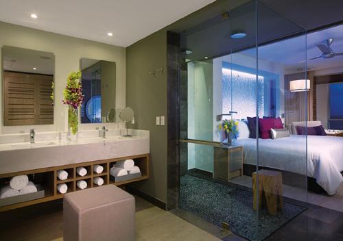 Breathless Riviera Cancun Resort & Spa - Adults Only - All inclusive في بويرتو موريلوس: غرفة نوم بسرير وحمام مع مرآة