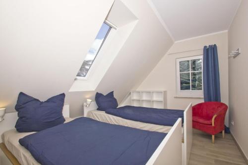 un dormitorio en el ático con 2 camas y una silla roja en Ferienhaus Auszeit FeWo 03 - Dachterrasse, ruhige Lage, en Middelhagen