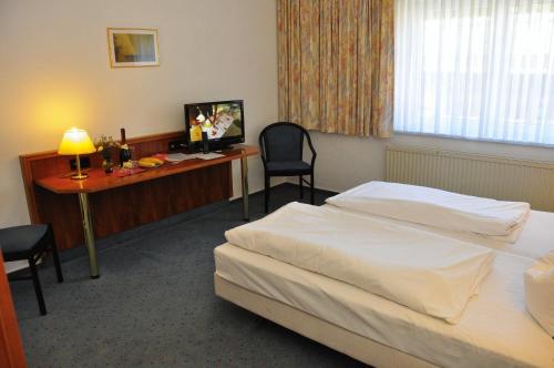 a hotel room with two beds and a desk at Brocki's Hotel Stadt Hamburg in Parchim