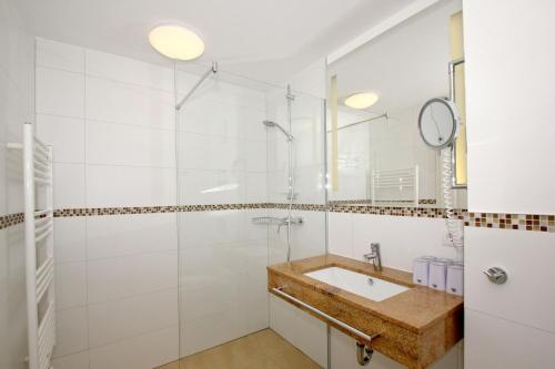 ein weißes Badezimmer mit Waschbecken und Dusche in der Unterkunft strandnahe FeWo mit Balkon, gratis Nutzung vom AHOI Erlebnisbad und Sauna in Sellin - Rex Rugia FeWo 10-7 in Lobbe