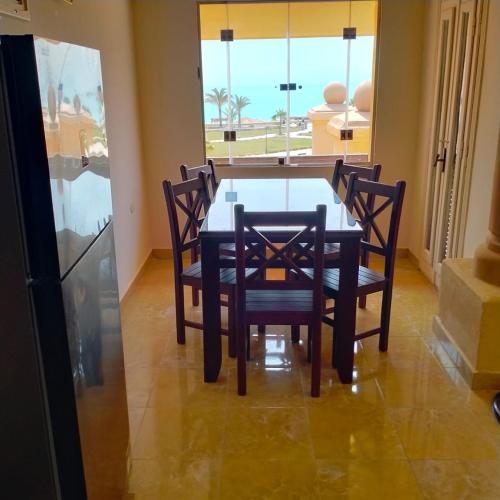 a dining room with a table and chairs and a window at Lazorde bay Sidi Abd El Rahman لازوردى باى apartment in El Alamein
