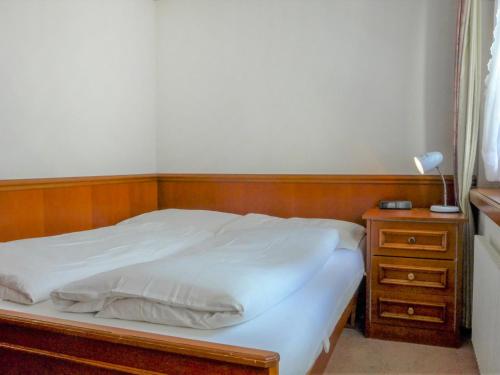 Bett mit einem Kopfteil aus Holz neben einem Nachttisch in der Unterkunft Apartment by Interhome in Zermatt
