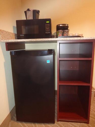 a kitchen with a microwave and a black refrigerator at Cobblestone Inn & Suites - Marquette in Marquette