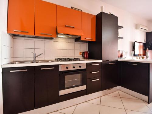 a kitchen with orange and black cabinets and a sink at Apartment Rosapanna-1 by Interhome in Rosapineta