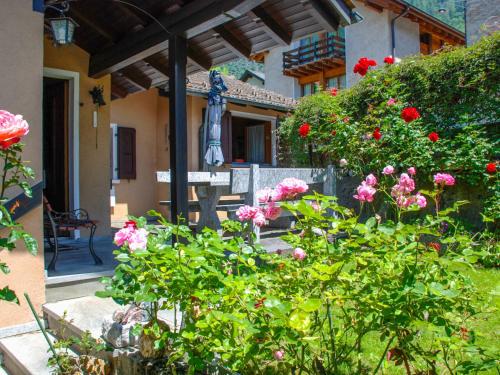 einen Garten mit rosa Blumen und einer Statue vor einem Gebäude in der Unterkunft Holiday Home La Casina by Interhome in Olivone