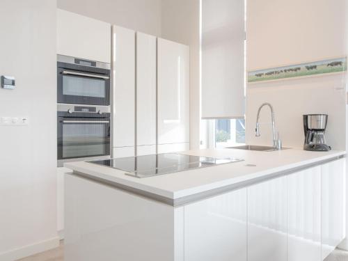 a white kitchen with a sink and a stove at Holiday Home Water Resort Oosterschelde - nr- 47A by Interhome in Wemeldinge