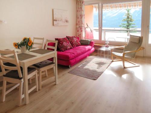 ein Wohnzimmer mit einem rosa Sofa und einem Tisch in der Unterkunft Apartment Promenade - Utoring-92 by Interhome in Arosa
