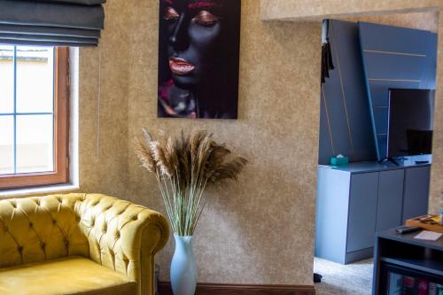 The Life Hotel & Spa في Yenimahalle: غرفة معيشة مع أريكة صفراء وصورة لامرأة