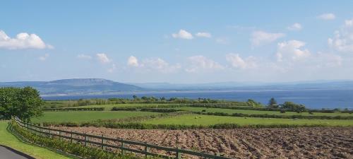 a view of a field with a fence and a lake at Knockalt Cottage in Moville