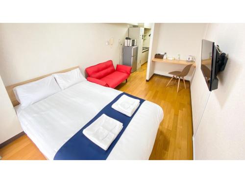 a bedroom with a bed and a red couch at HOTEL Nishikawaguchi Weekly - Vacation STAY 43454v in Saitama