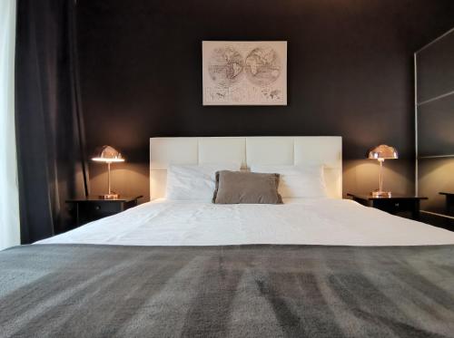 - une chambre avec un grand lit blanc et deux lampes dans l'établissement Wonderful Apartment near City Mall, à Podgorica