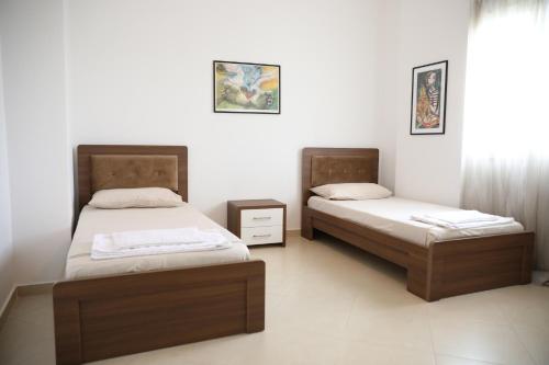 two beds in a room with white walls at Square View Apartment in Vlorë